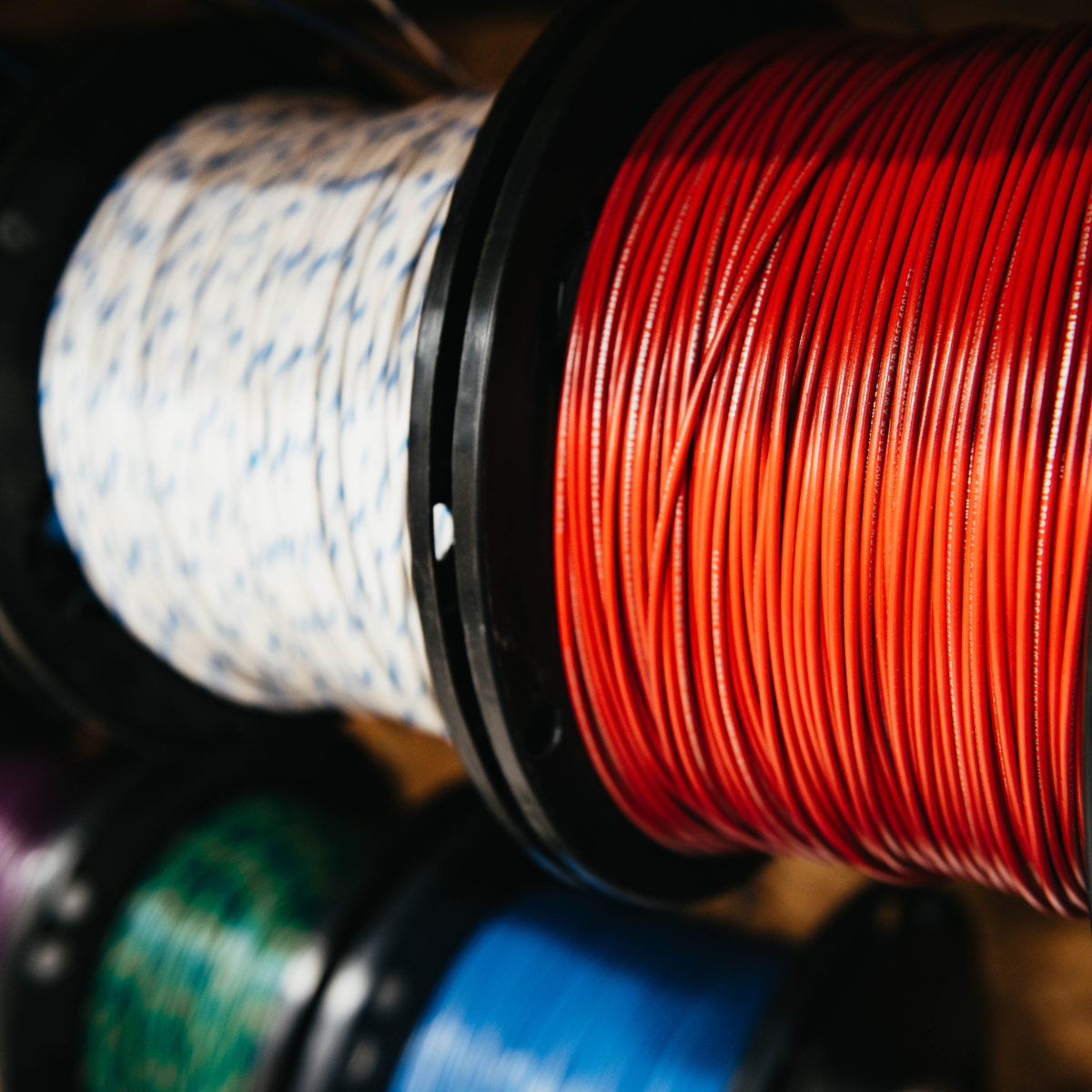 Rolled white, orange, green and blue wire on spools